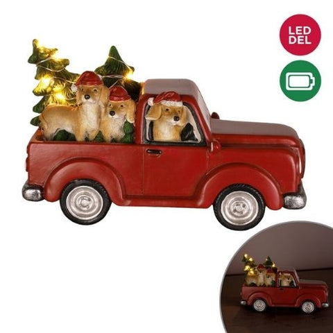 Camion rouge lumineux avec trois chiens et sapins
