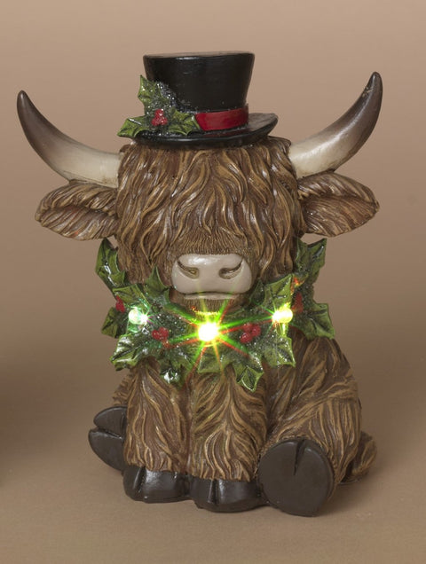 Vache Highland festive en résine avec chapeau et guirlande lumineuse